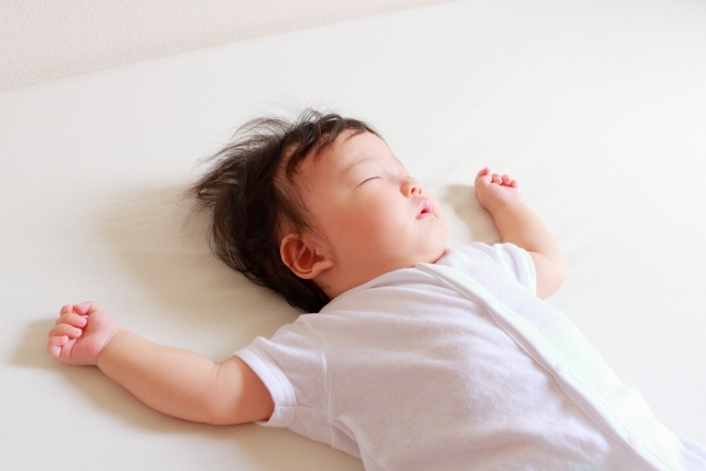 白いシーツの上で眠る赤ちゃん