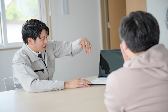 ノートパソコンを使って説明する作業服姿の担当者